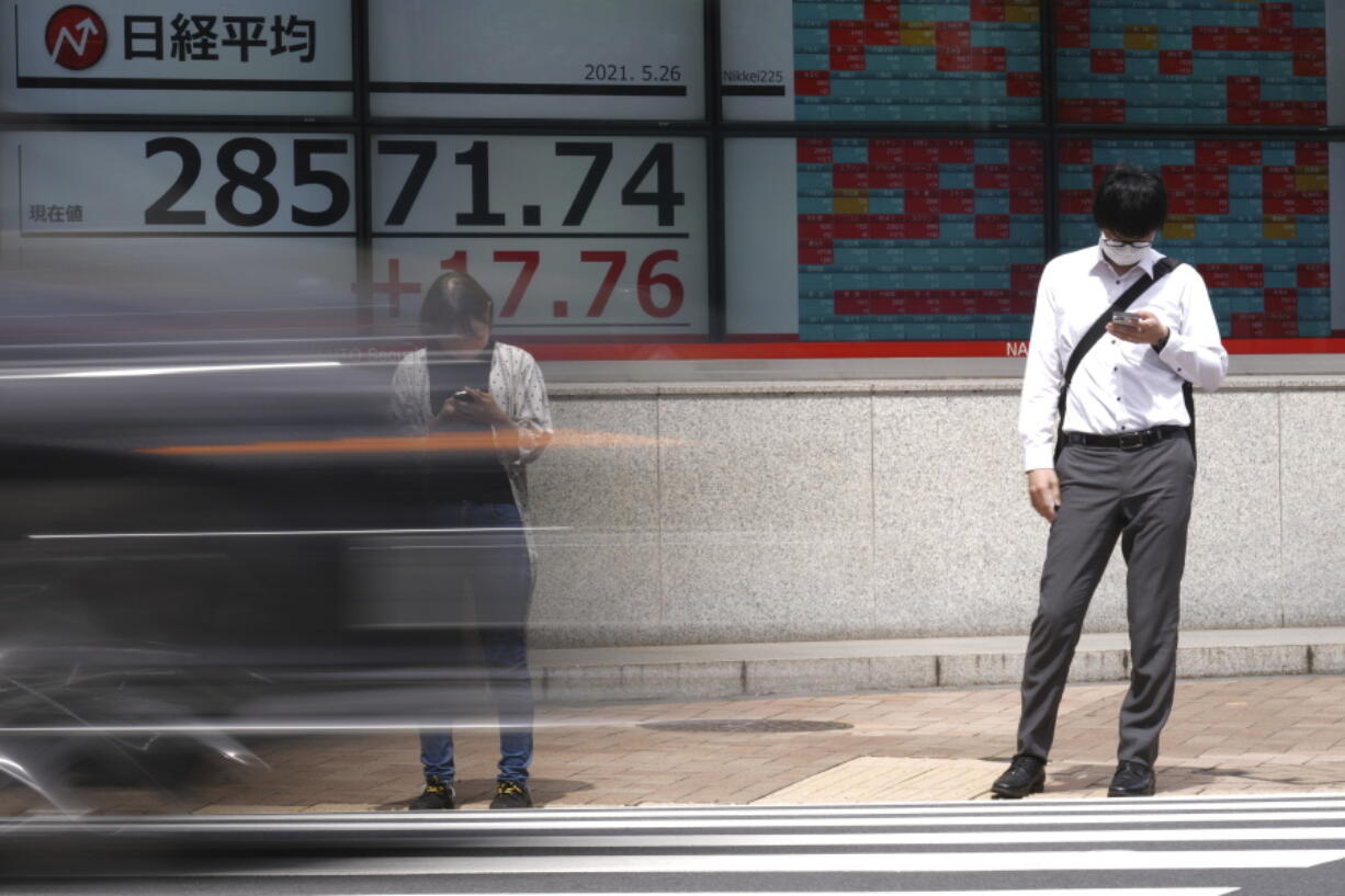 A man and a woman wearing protective masks stand in front of an electronic stock board showing Japan's Nikkei 225 index at a securities firm Wednesday, May 26, 2021, in Tokyo. Asian stock markets rose Wednesday as inflation fears eased and investors looked ahead to U.S. data that are expected to show economic growth accelerating.