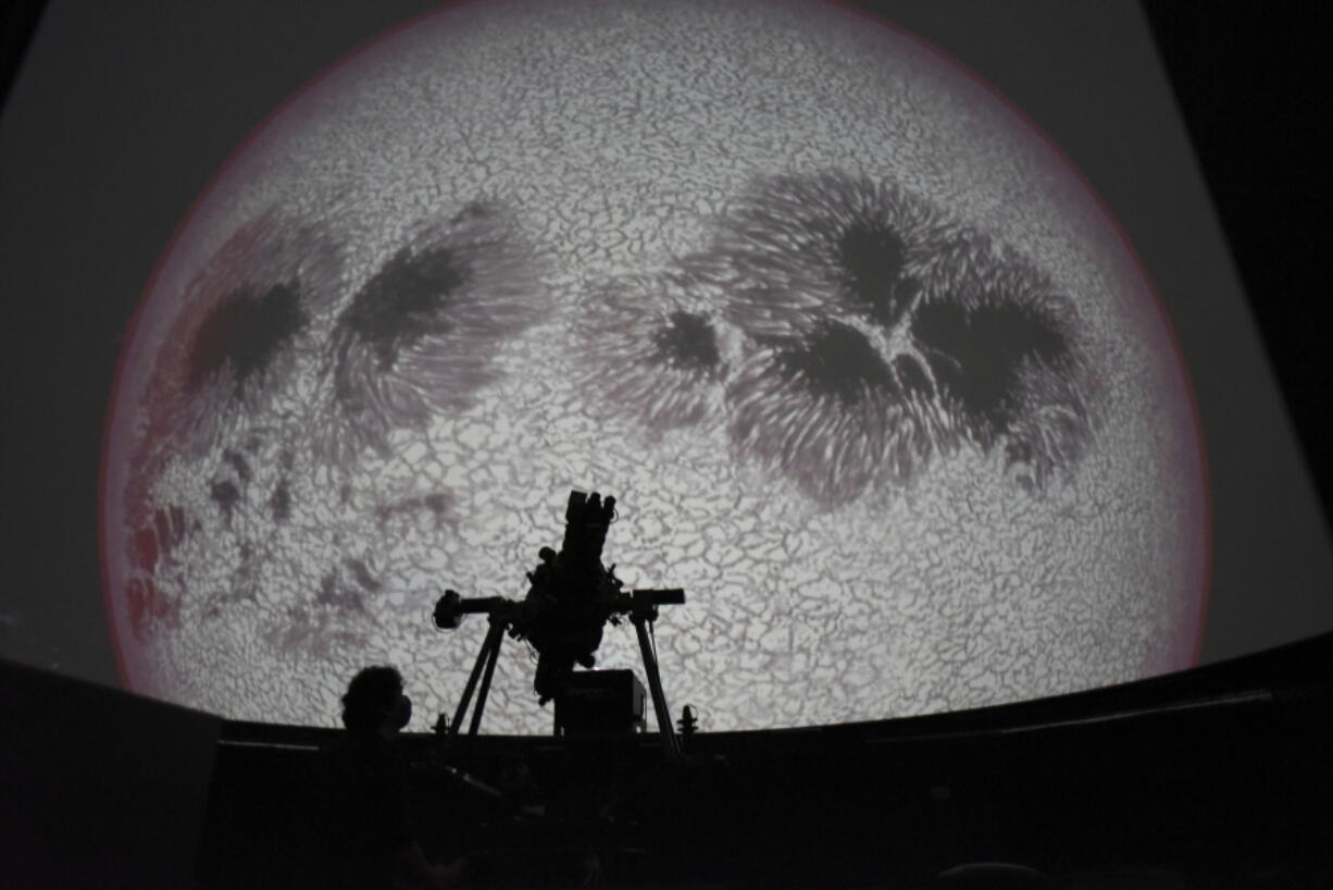 Researcher Ivannia Calvo, silhouetted against a solar satellite image, works inside the Solar Astronomical Observatory in San Jose, Costa Rica, Friday, April 30, 2021. Costa Rica approved a law creating a space agency on Feb. 18.