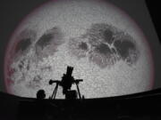 Researcher Ivannia Calvo, silhouetted against a solar satellite image, works inside the Solar Astronomical Observatory in San Jose, Costa Rica, Friday, April 30, 2021. Costa Rica approved a law creating a space agency on Feb. 18.