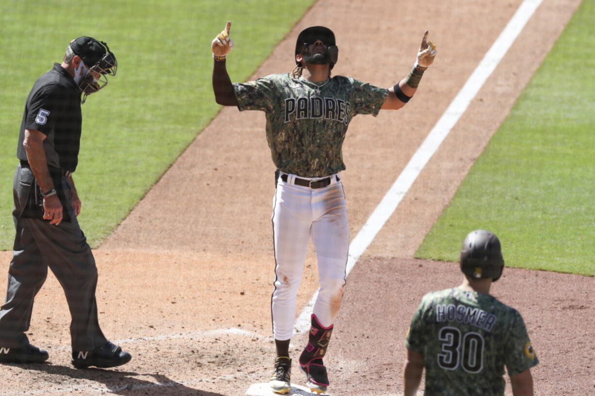 San Diego Padres' Fernando Tatis Jr., center, points skyward as he crosses home plate after hitting a grand slam off Seattle Mariners relief pitcher Robert Dugger in the seventh inning of a baseball game Sunday, May 23, 2021, in San Diego.