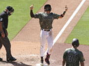 San Diego Padres' Fernando Tatis Jr., center, points skyward as he crosses home plate after hitting a grand slam off Seattle Mariners relief pitcher Robert Dugger in the seventh inning of a baseball game Sunday, May 23, 2021, in San Diego.