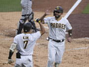 San Diego Padres' Eric Hosmer, right, is congratulated by Ha-Seong Kim (7) after scoring against the Seattle Mariners during the fifth inning of a baseball game Saturday, May 22, 2021, in San Diego.