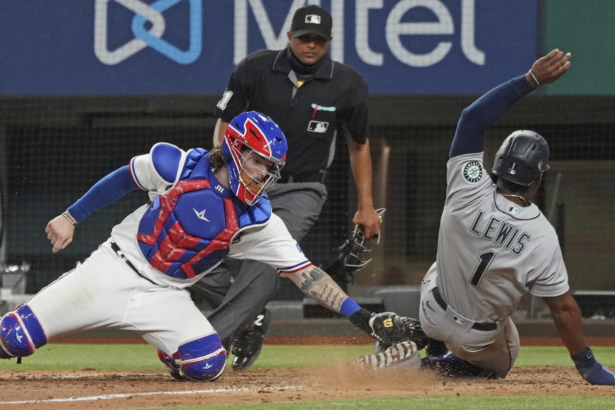 Seattle Mariners base runner Kyle Lewis is tagged out at home by Texas Rangers catcher Jonah Heim to end a baseball game in the ninth inning Saturday, May 8, 2021, in Arlington, Texas.