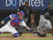 Seattle Mariners base runner Kyle Lewis is tagged out at home by Texas Rangers catcher Jonah Heim to end a baseball game in the ninth inning Saturday, May 8, 2021, in Arlington, Texas.