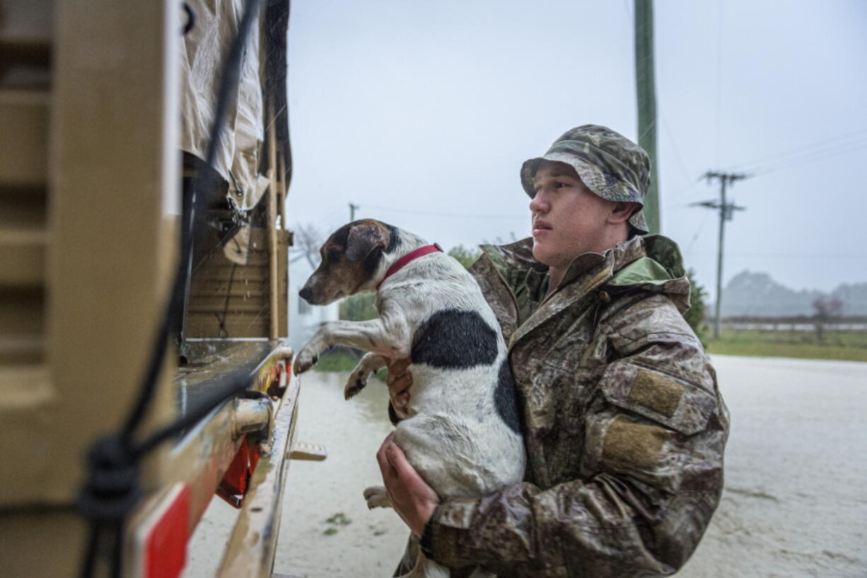 A member of the New Zealand Defense Force rescues a dog from floods as they assist a family with their evacuation near Ashburton in New Zealand's South Island, Sunday May 30, 2021. Several hundred people in New Zealand were evacuated from their homes Monday, May 31, 2021 as heavy rainfall caused flooding in the Canterbury region. (Corp.