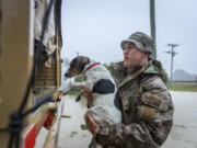 A member of the New Zealand Defense Force rescues a dog from floods as they assist a family with their evacuation near Ashburton in New Zealand's South Island, Sunday May 30, 2021. Several hundred people in New Zealand were evacuated from their homes Monday, May 31, 2021 as heavy rainfall caused flooding in the Canterbury region. (Corp.