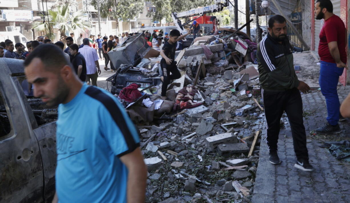 People inspect the rubble of destroyed the Abu Hussein building that was hit by an Israeli airstrike early morning, in Gaza City, Wednesday, May 19, 2021.