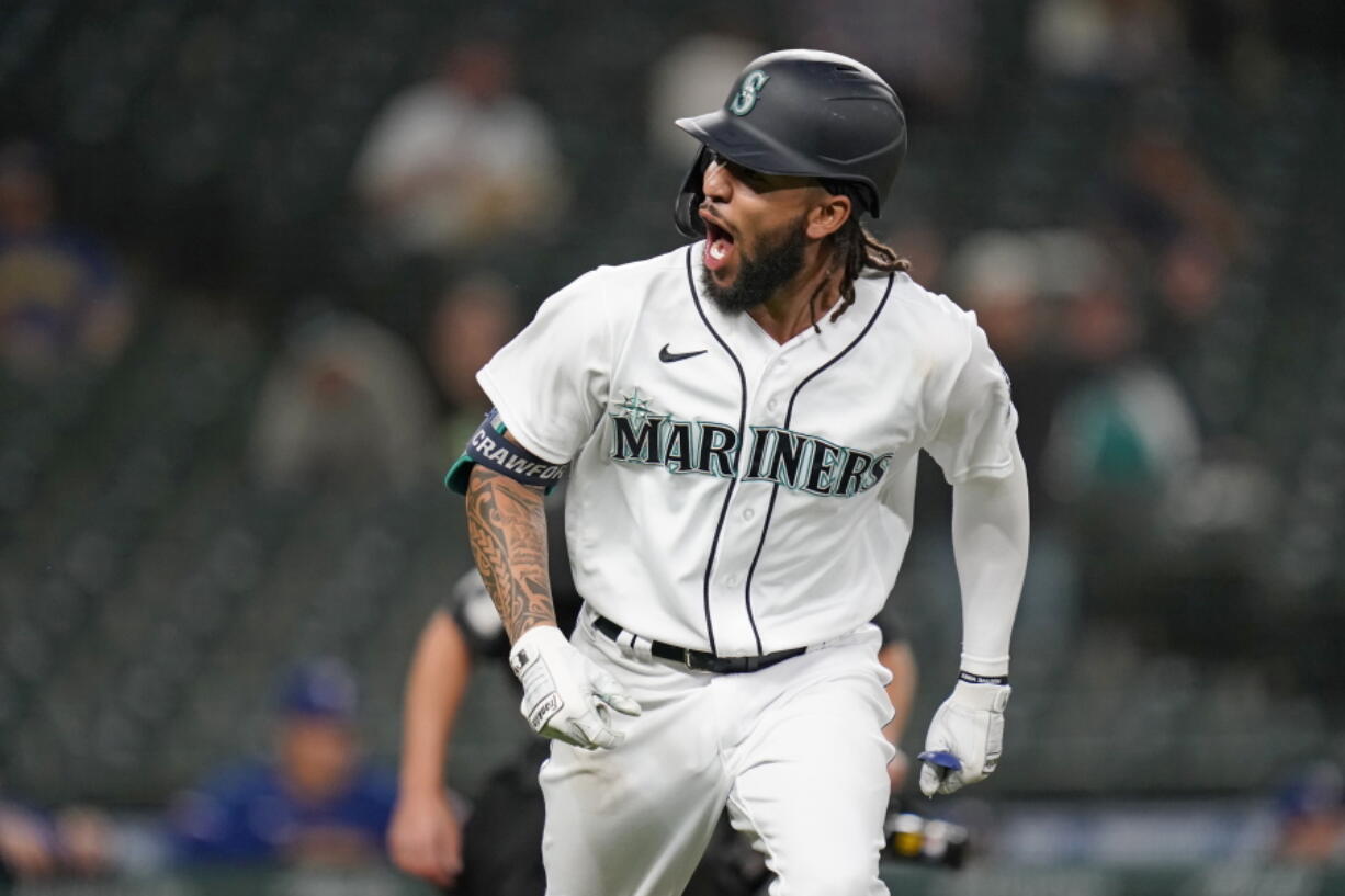 Seattle Mariners' J.P. Crawford turns toward the team dugout and lets out a yell as he begins to round the bases on his solo home run against the Texas Rangers during the seventh inning of a baseball game Saturday, May 29, 2021, in Seattle.