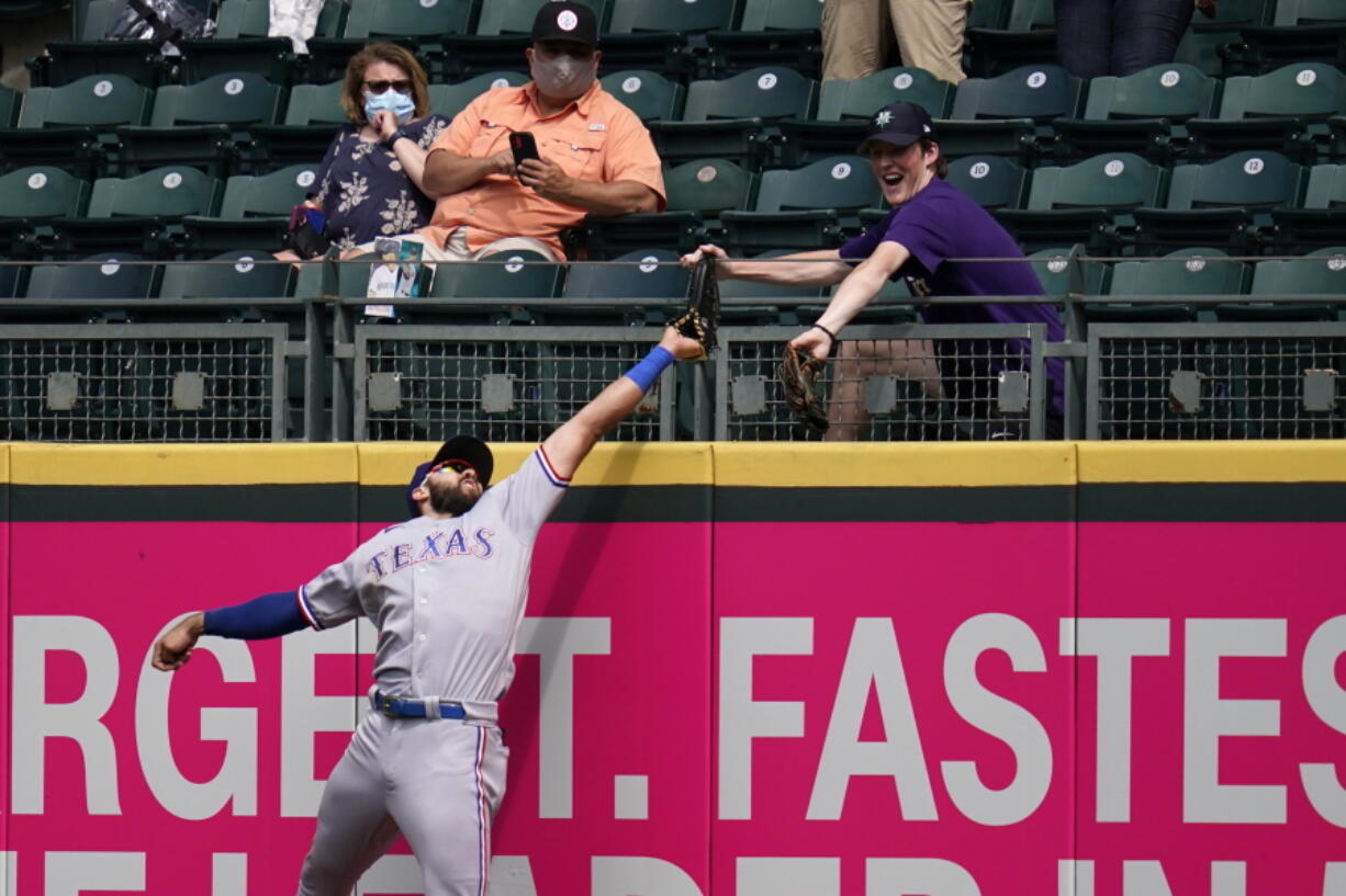 Texas Rangers right fielder Joey Gallo and a fan compete for the home run ball of Seattle Mariners' Kyle Seager in the fifth inning of a baseball game Sunday, May 30, 2021, in Seattle.