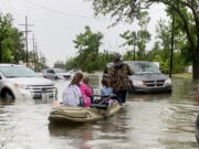 Parents use boats to pick up students from schools after nearly a foot of rain fell in Lake Charles, La., Monday, May 17, 2021.