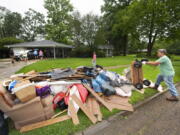 Homeowner Stephen Punkay, right, dumps a cart-load of wet carpet to add to the debris pile, after the Baker Drive home that he and wife Amy share with their six children got at least six inches of water in Monday night's deluge of rain in the Westminster subdivision, as they clean up with the help of family, neighbors and "church family" from Community Bible Church, on Tuesday, May 18, 2021, in Baton Rouge, La. Heavy rains have swept across southern Louisiana, flooding homes, swamping cars and closing a major interstate.