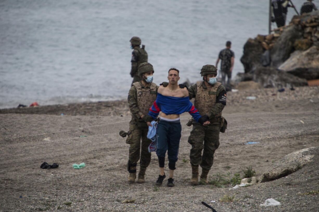 A man from Morocco is detained by soldiers of the Spanish Army at the border of Morocco and Spain, at the Spanish enclave of Ceuta, on Tuesday, May 18, 2021. Ceuta, a Spanish city of 85,000 in northern Africa, faces a humanitarian crisis after thousands of Moroccans took advantage of relaxed border control in their country to swim or paddle in inflatable boats into European soil. Around 6,000 people had crossed by Tuesday morning since the first arrivals began in the early hours of Monday, including 1,500 who are presumed to be teenagers.