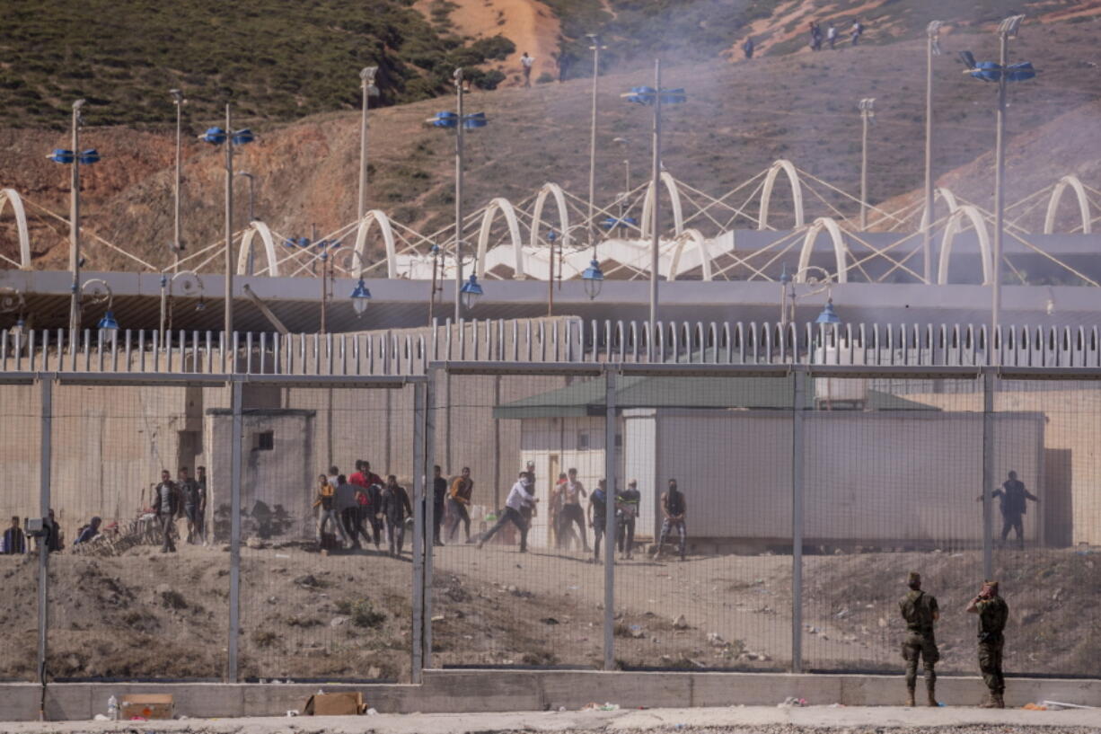 Boys throw stones towards Spanish security forces at the border of Morocco and Spain, Wednesday, May 19, 2021. Spain's north African enclave of Ceuta has awakened to a humanitarian crisis after thousands of migrants who crossed over from Morocco spent the night sleeping where they could find shelter. Social services for the small city perched on an outcropping in the Mediterranean buckled under the strain after more than 8,000 people crossed into Spanish territory during the previous two days.