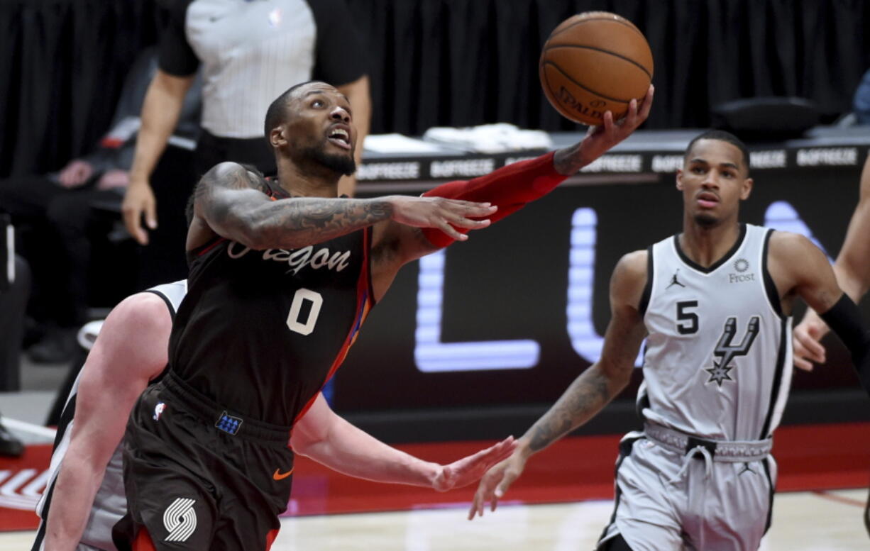 Portland Trail Blazers guard Damian Lillard, left, shoots as San Antonio Spurs guard Dejounte Murray, right, watches during the second half of an NBA basketball game in Portland, Ore., Saturday, May 8, 2021.