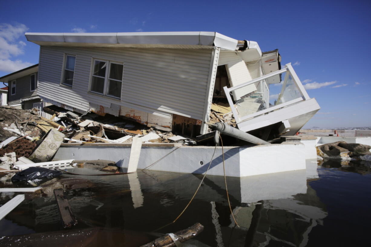 FILE - In this Thursday, Jan. 31, 2013 file photo, a storm-damaged beachfront house is reflected in a pool of water in the Far Rockaways, in the Queens borough of New York. A study released in the journal Nature Communications on Tuesday, May 18, 2021, says climate change added $8 billion to the massive costs of 2012's Superstorm Sandy.