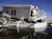 FILE - In this Thursday, Jan. 31, 2013 file photo, a storm-damaged beachfront house is reflected in a pool of water in the Far Rockaways, in the Queens borough of New York. A study released in the journal Nature Communications on Tuesday, May 18, 2021, says climate change added $8 billion to the massive costs of 2012's Superstorm Sandy.