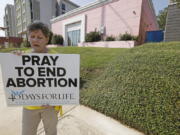 FILE - In this Oct. 2, 2019. file photo, an abortion opponent sings to herself outside the Jackson Womens Health Organization clinic in Jackson, Miss. The Supreme Court has agreed to hear a potentially ground-breaking abortion case, and the news is energizing activists on both sides of the contentious issue. They're already girding to make abortion access a high-profile issue in next year's midterm elections. (AP Photo/Rogelio V.