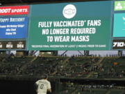 Fans sit in a special section for people who are fully vaccinated against COVID-19, at T-Mobile Park during a baseball game between the Seattle Mariners and the Detroit Tigers, Monday, May 17, 2021, in Seattle. Monday was the first day that fans fully vaccinated against COVID-19 were not required to wear masks at the ballpark, as shown on the video display. (AP Photo/Ted S.