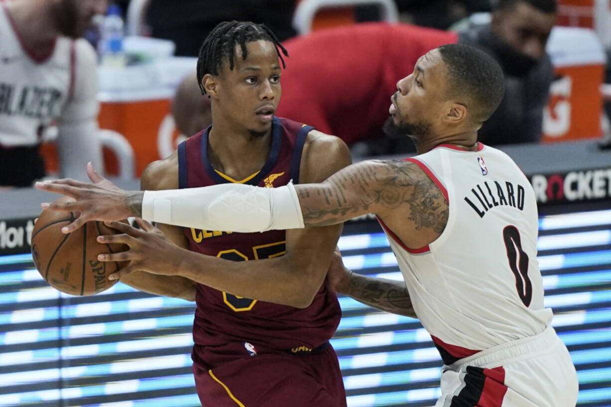 Portland Trail Blazers' Damian Lillard (0) defends against Cleveland Cavaliers' Isaac Okoro during the second half of an NBA basketball game Wednesday, May 5, 2021, in Cleveland.