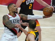 Portland Trail Blazers guard Damian Lillard, left, lays the ball up as Utah Jazz forward Bojan Bogdanovic, right, watches during the second half of an NBA basketball game Wednesday, May 12, 2021, in Salt Lake City.