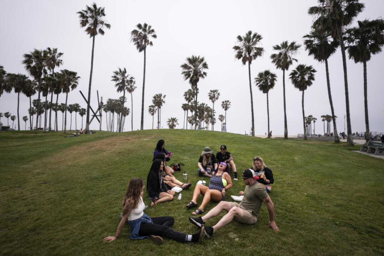 FILE - In this May 5, 2021, file photo, a group of friends, who said they are fully vaccinated for COVID-19, mingle on the beach in the Venice section of Los Angeles. COVID-19 deaths in the U.S. have tumbled to an average of just over 600 per day - the lowest level in 10 months - with the number of lives lost dropping to single digits in well over half the states and hitting zero on some days. (AP Photo/Jae C.