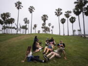 FILE - In this May 5, 2021, file photo, a group of friends, who said they are fully vaccinated for COVID-19, mingle on the beach in the Venice section of Los Angeles. COVID-19 deaths in the U.S. have tumbled to an average of just over 600 per day - the lowest level in 10 months - with the number of lives lost dropping to single digits in well over half the states and hitting zero on some days. (AP Photo/Jae C.