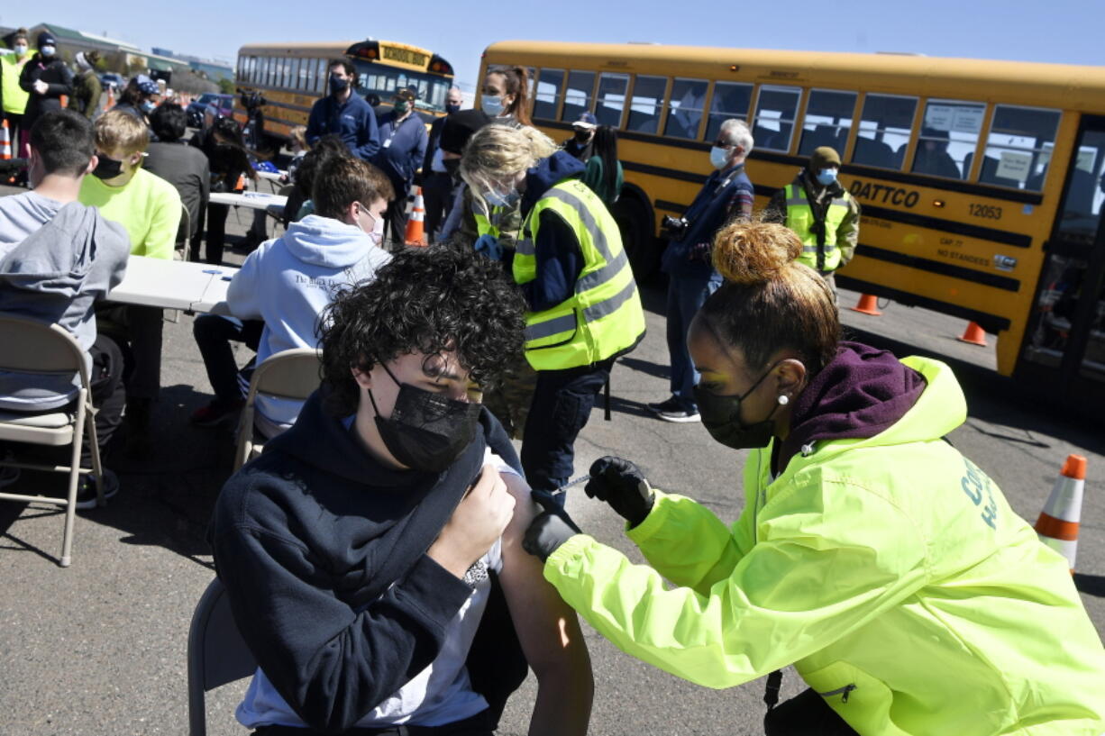 FILE - In this April 26, 2021, file photo, CREC Academy of Aerospace and Engineering sophomore Brian Acevedo, 16, receives a COVID-19 vaccine from nurse Myra Glass, of East Hartford, during a mass vaccination site at Pratt & Whitney Runway in East Hartford, Conn. Teams of experts are projecting COVID-19's toll on the U.S. will fall sharply by the end of July, according to research released by the government Wednesday, May 5.