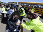 FILE - In this April 26, 2021, file photo, CREC Academy of Aerospace and Engineering sophomore Brian Acevedo, 16, receives a COVID-19 vaccine from nurse Myra Glass, of East Hartford, during a mass vaccination site at Pratt & Whitney Runway in East Hartford, Conn. Teams of experts are projecting COVID-19's toll on the U.S. will fall sharply by the end of July, according to research released by the government Wednesday, May 5.