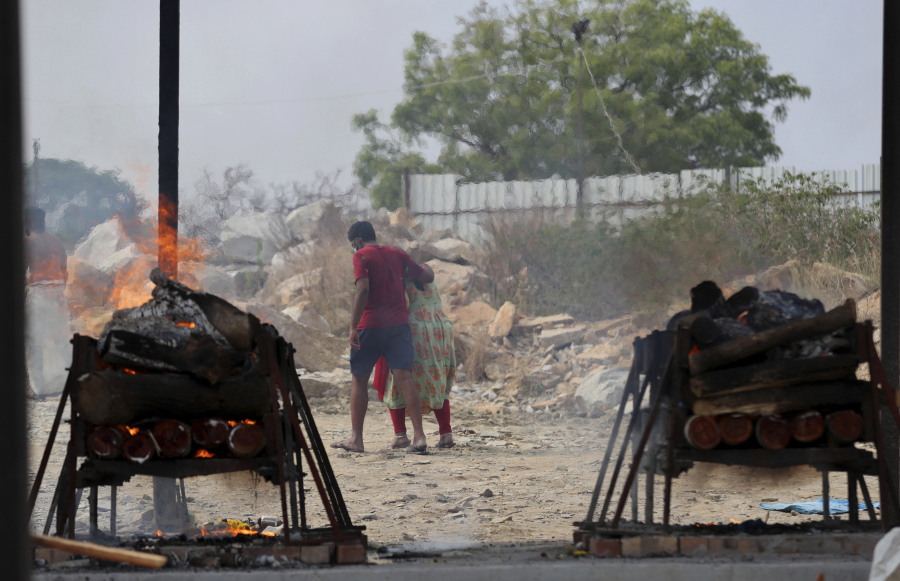 Family members of COVID-19 victims leave as their funeral pyres burn at an open crematorium set up at a granite quarry on the outskirts of Bengaluru, India, Wednesday, May 5, 2021.