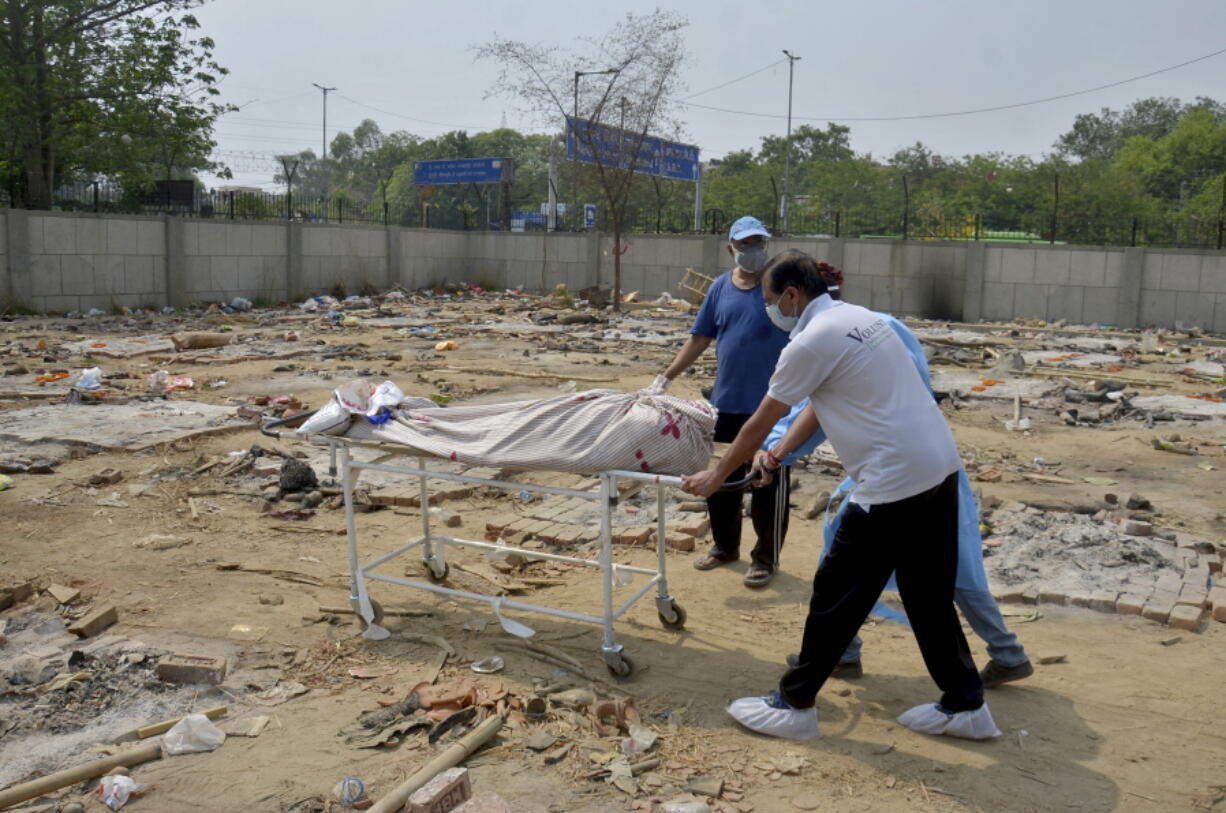 Body of a COVID-19 victim is wheeled in a ground that has been converted into a crematorium in New Delhi, India, Saturday, May 1, 2021. India on Saturday set yet another daily global record with 401,993 new cases, taking its tally to more than 19.1 million. Another 3,523 people died in the past 24 hours, raising the overall fatalities to 211,853, according to the Health Ministry. Experts believe both figures are an undercount.