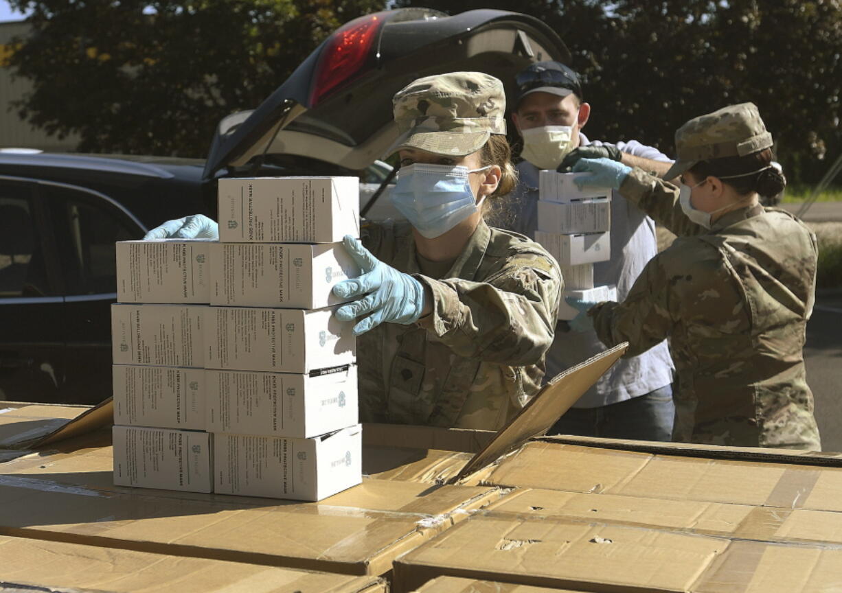 FILE - In this Wednesday, May 27, 2020, file photo, Oregon National Guard's Ashley Smallwood, of Springfield, Ore., counts out boxes of face masks to be given to Willamette Valley farmers while participating in a distribution event at the Oregon State University Extension Service-Linn County office in Tangent, Ore. Oregon adopted a controversial rule on Tuesday, May 4, 2021 that indefinitely extends coronavirus mask and social distancing requirements in all businesses in the state.