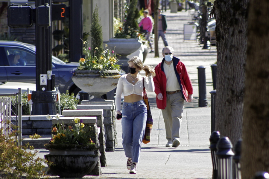 FILE - In this April 11, 2021, file photo, residents wearing masks walk in downtown Lake Oswego, Ore.