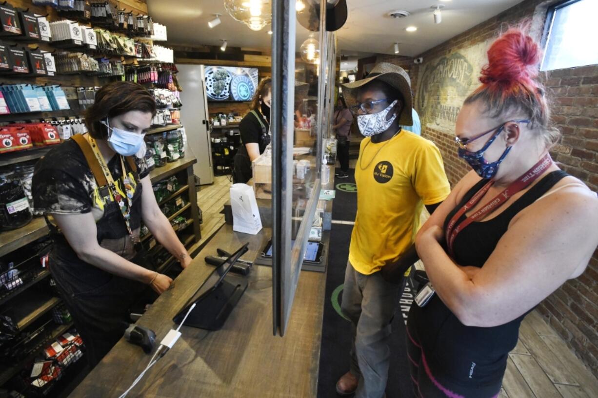 Budtender Kelley Dearing helps customers Timothy Benison and Sharon Stricklan with their purchases at the Greenhouse, a recreational and medical marijuana dispensary, in Walled Lake, Michigan on June 7, 2021.