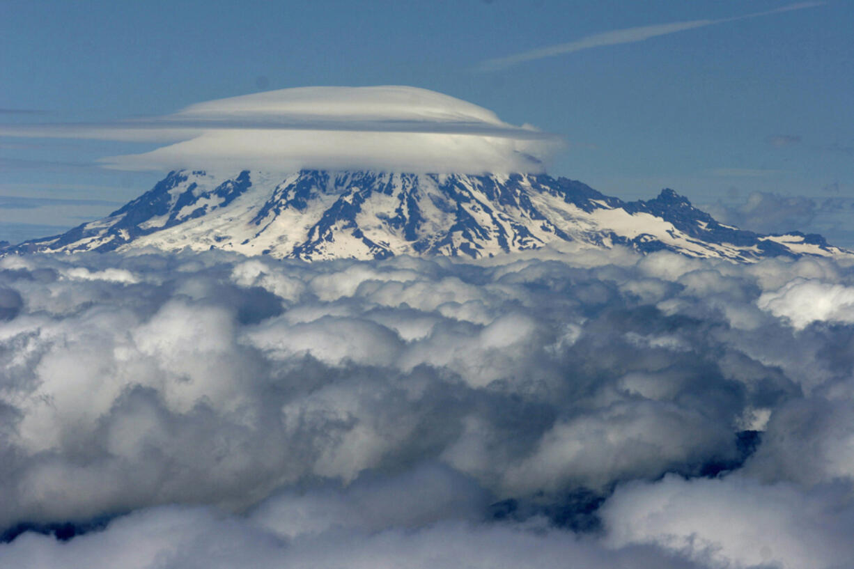 The summit of Mount Rainier, blanketed with cloud cover, as seen from the top of Mount St. Helens.