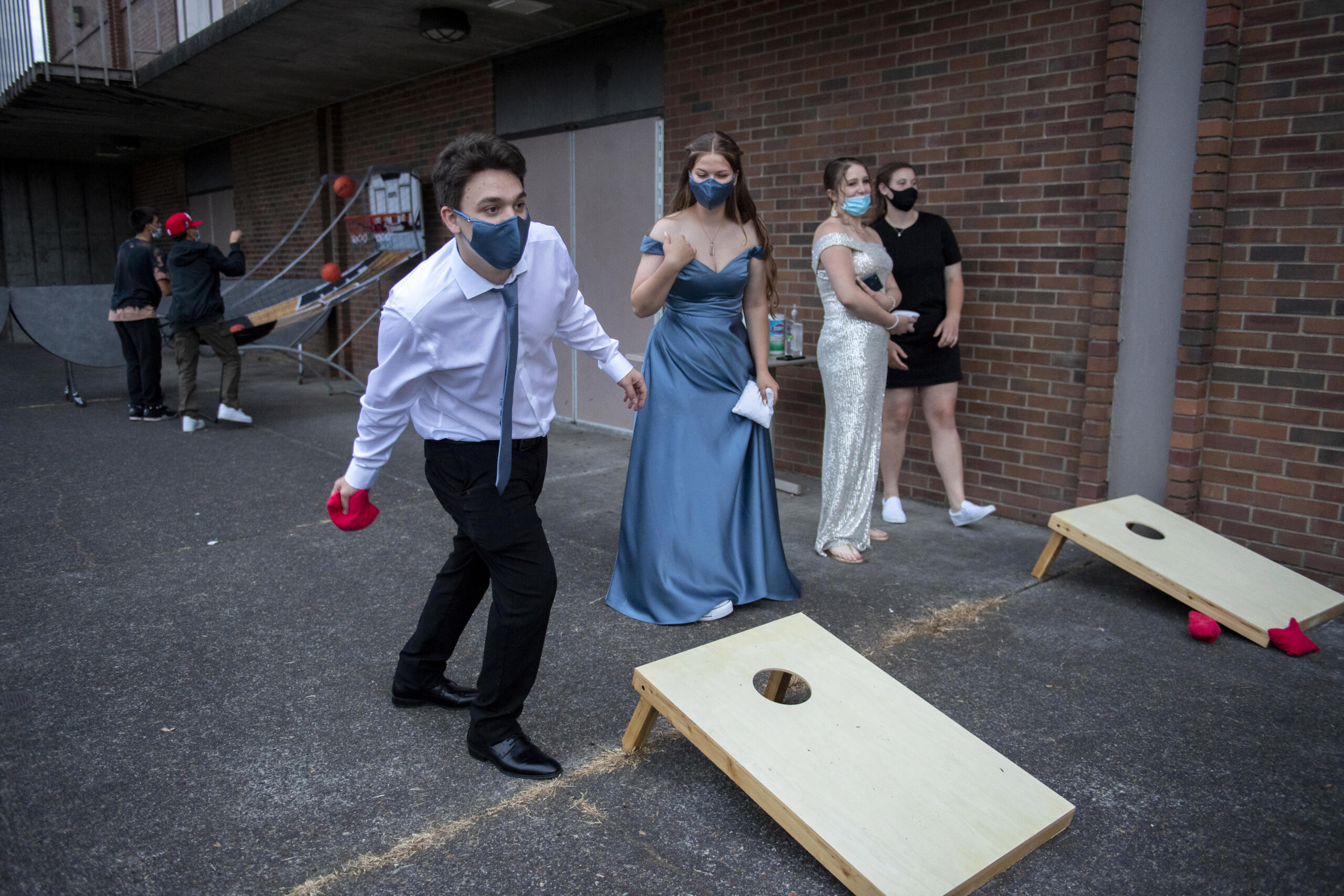 Junior Chris Boone, 18, left, takes aim while playing cornhole with fellow junior Emma Garrett, 16, outside the gym at Fort Vancouver High School on May 22. The games were part of the outdoor entertainment option for students at the unique prom, not only to offer activities as a secondary option, but also a safe outside alternative in case students didn’t feel comfortable indoors as the COVID-19 pandemic continues.