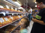 Eileen Baye, 2, left, of Vancouver and her brother, Dylan, 9, look over the selection at the Donut Nook.