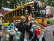 Students including first-grader Trulee Dunn, right, get a warm goodbye from teachers as they prepare to board the bus on the last day of class at Green Mountain School on Tuesday morning. It is tradition for teachers and staff to blow bubbles to bid farewell to the children but this year a bubble machine was used as well.