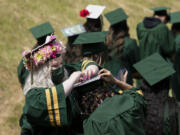 A graduate helps her friend fix the decorations on her graduation cap at the Evergreen High School graduation ceremony on Saturday, June 12, at McKenzie Stadium.