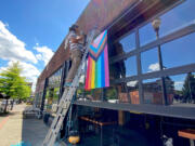 A Thirsty Sasquatch employee hangs new LGBTQ Pride banners Wednesday. Vandals tore down the old banners and smeared feces on the premises.