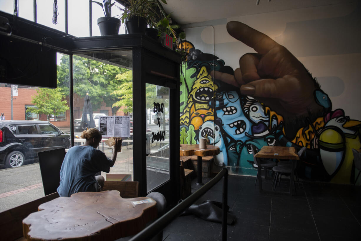 Server Bilen Solscheid cleans the windows at The Thirsty Sasquatch while preparing for customers Monday in Uptown Village. The location includes a craft cocktail and coffee bar, pizza parlor, arcade room and two outdoor patios.