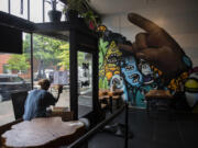 Server Bilen Solscheid cleans the windows at The Thirsty Sasquatch while preparing for customers Monday in Uptown Village. The location includes a craft cocktail and coffee bar, pizza parlor, arcade room and two outdoor patios.