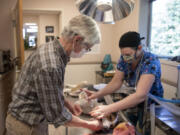 Dr. David Slocum, left, joins vet assistant Jessie Dohse as they prepare patient Molly, 1, a hound mix, to be spayed at Hazel Dell Animal Hospital.  Slocum, 73, has worked at the same clinic since he was 14 years old. He plans to sell the clinic this year but will still help homeless people and their pets who need veterinary care.