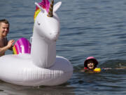 Slava Bakhmutov holds an inflatable rainbow unicorn while Arriana, 4, swims toward it after she fell off on Saturday morning, June 26, at Cottonwood Beach in Washougal. “She’s rainbow obsessed,” Arianna’s mother said. Temperatures climbed into triple digits on Saturday, the first of three days it is expected to do so.