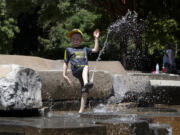 Henry Lester, 5, kicks water on Friday at the water feature in Esther Short Park, which opened on Thursday. Temperatures are expected to climb into the triple digits over the weekend.