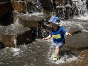 Robin Lester, 2, jumps into the shallow water to make a splash on Friday, June 25, 2021, at the Esther Short Water Feature.