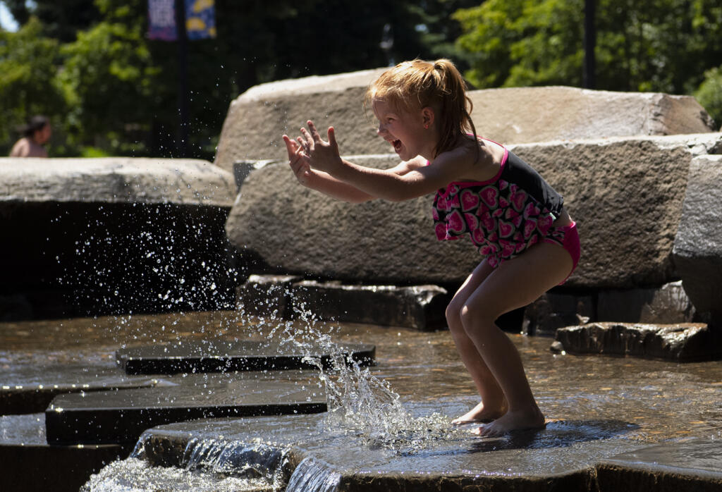 Cheyanne Peters, 6, splashes water toward her mom while giggling on Friday, June 25, 2021, at the Esther Short Water Feature. Temperatures are expected to climb into the triple digits for the next three days.