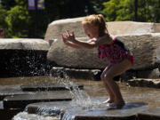 Cheyanne Peters, 6, splashes water toward her mom while giggling on Friday, June 25, 2021, at the Esther Short Water Feature. Temperatures are expected to climb into the triple digits for the next three days.