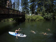 Swimmers join a stand-up paddleboarder as they gather to beat the extreme heat at Lacamas Park on Monday afternoon, June 28, 2021.