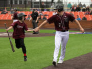 Ridgefield's Caden Connor (7) celebrates with bat boy Colton Schreiber, 9, of Battleground, after scoring a run against Bellingham during the second inning of a West Coast League baseball game  at the Ridgefield Outdoor Recreation Complex on Wednesday, June 30, 2021.