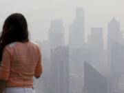 A woman looks at the skyline from the Space Needle observation deck on Monday, August 20, 2018 in Seattle.